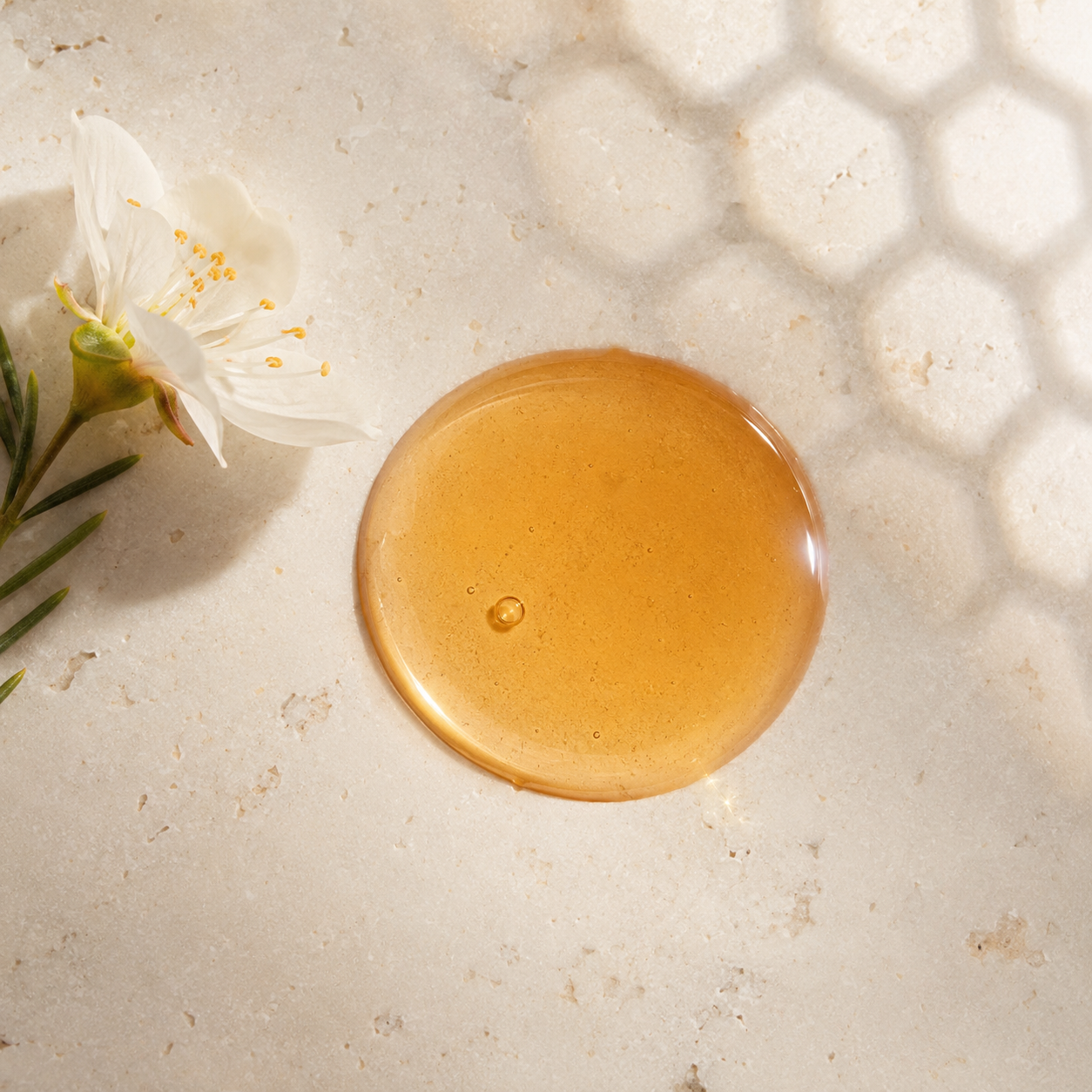 Glossy amber bee venom facial serum texture on warm white stone