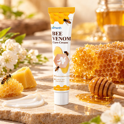 ximonth Bee Venom Care Cream 20g tube on stone with honeycomb, beeswax and a honey dipper