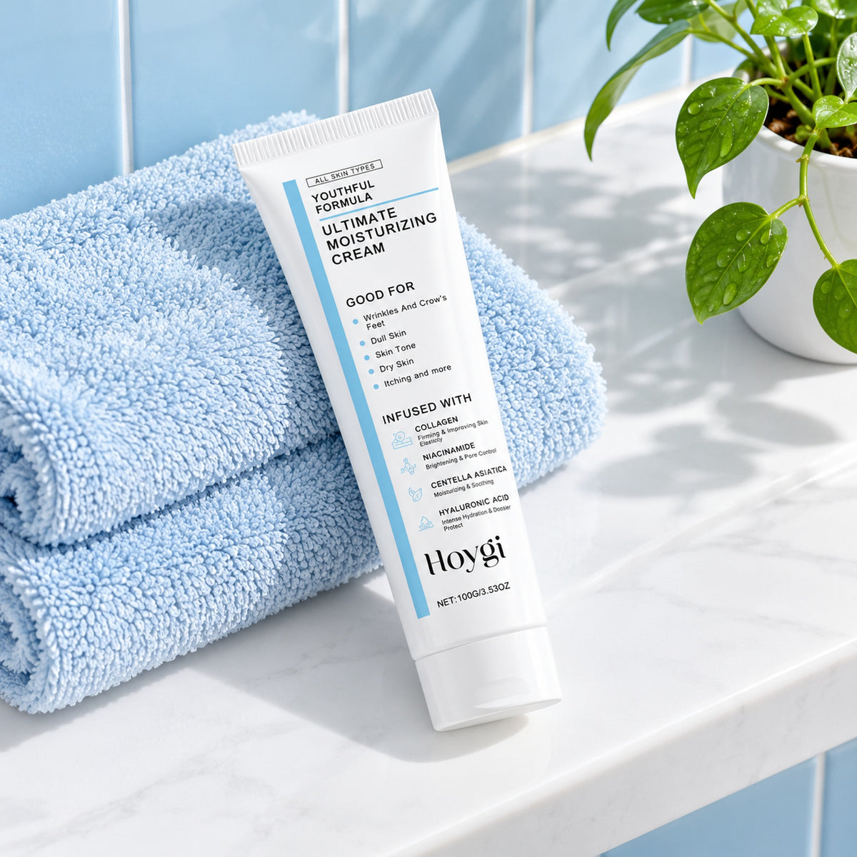 Hoygi Ultimate Moisturizing Cream 100g tube on a bathroom shelf with a blue towel and a plant