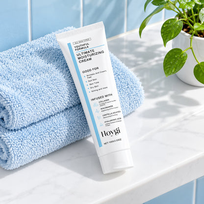 Hoygi Ultimate Moisturizing Cream 100g tube on a bathroom shelf with a blue towel and a plant