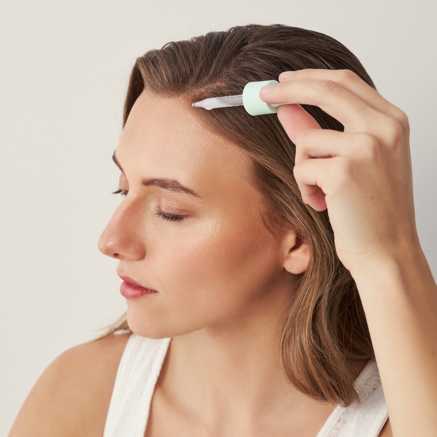 Applying Divi Scalp Serum to the scalp with the dropper
