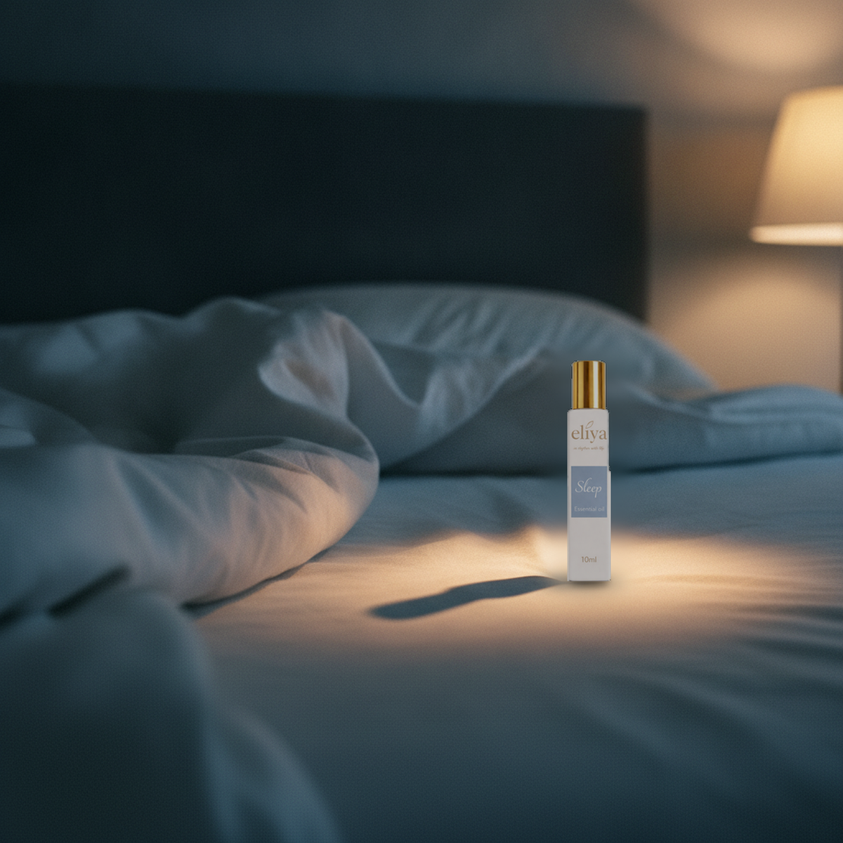 eliya Sleep roller standing in a small pool of bedside lamplight on a turned-down bed at night