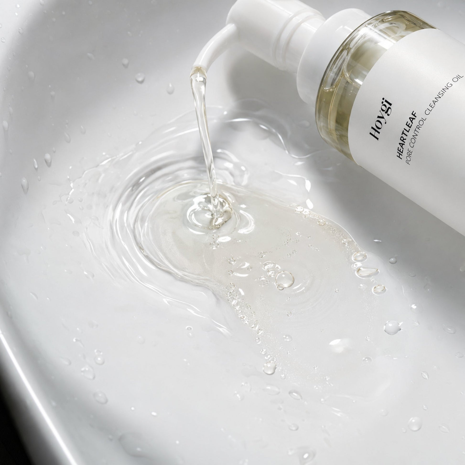 Hoygi pump dispensing clear cleansing oil into water for a macro emulsification view