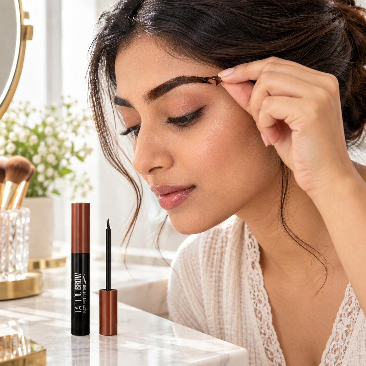 Woman peeling the dried Tattoo Brow tint film from her brow at a vanity