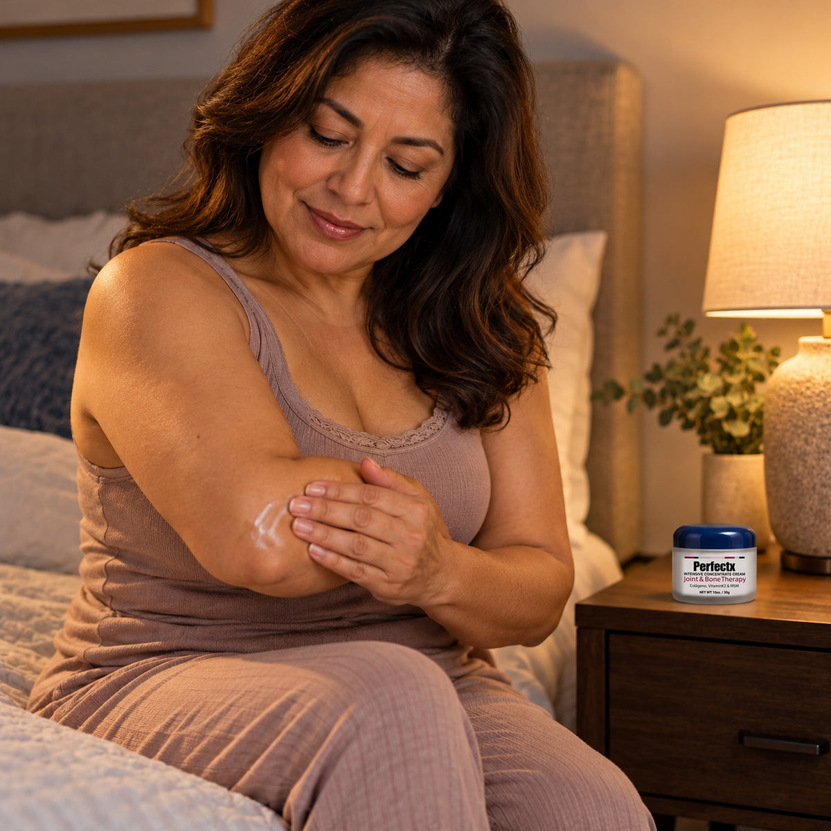 Woman massaging Perfectx balm into her elbow at bedtime, jar on the nightstand
