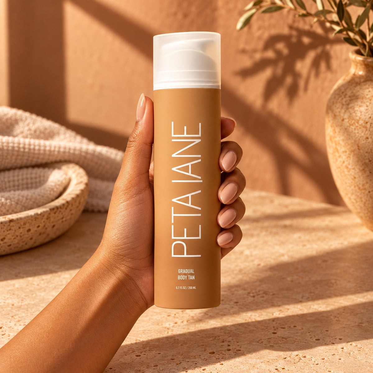 Hand holding the 200 ml PETA JANE gradual body tan bottle for size