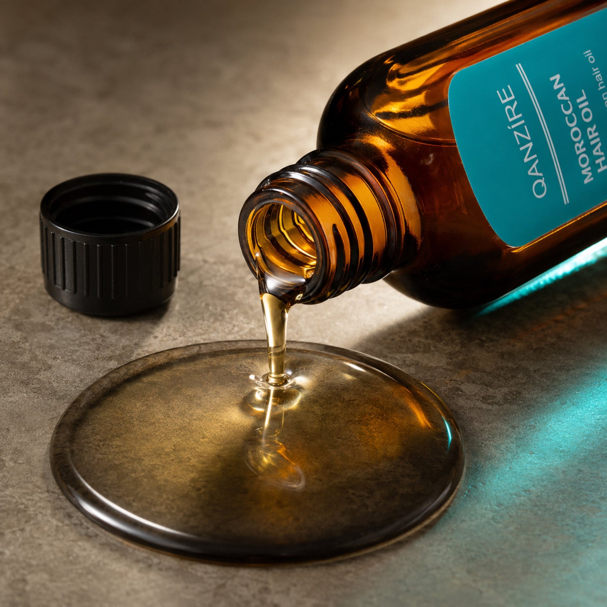 QANZIRE bottle pouring silky golden hair oil from its screw-cap opening in macro detail