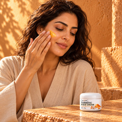 Woman smoothing golden turmeric cream onto her cheek in warm morning light, jar on the counter