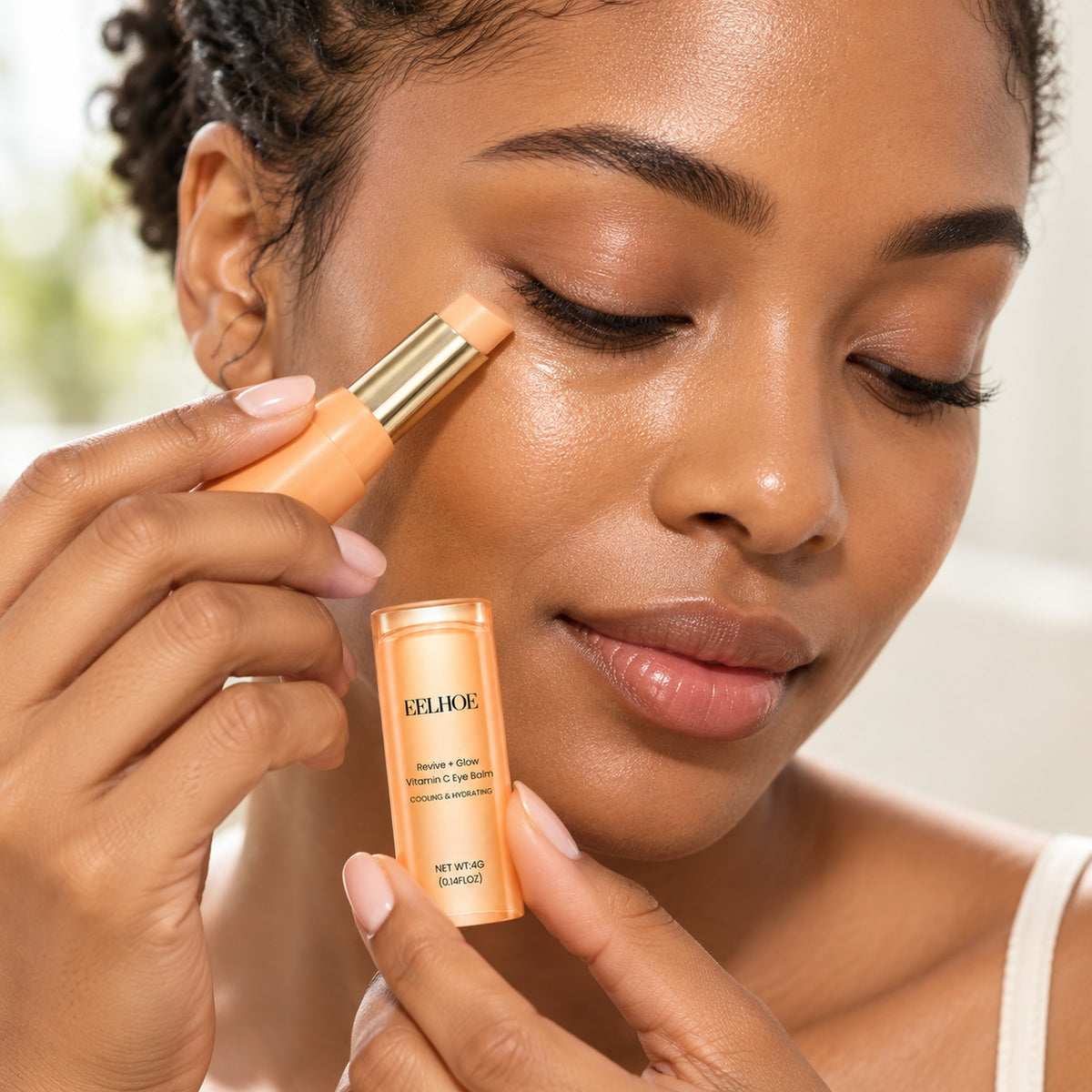 Woman gliding the Vitamin C eye balm stick under her eye